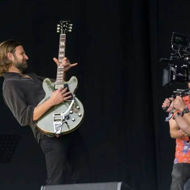 bradley cooper guitarist playing guitar filming 'A Star Is Born' in Glastonbury festival.